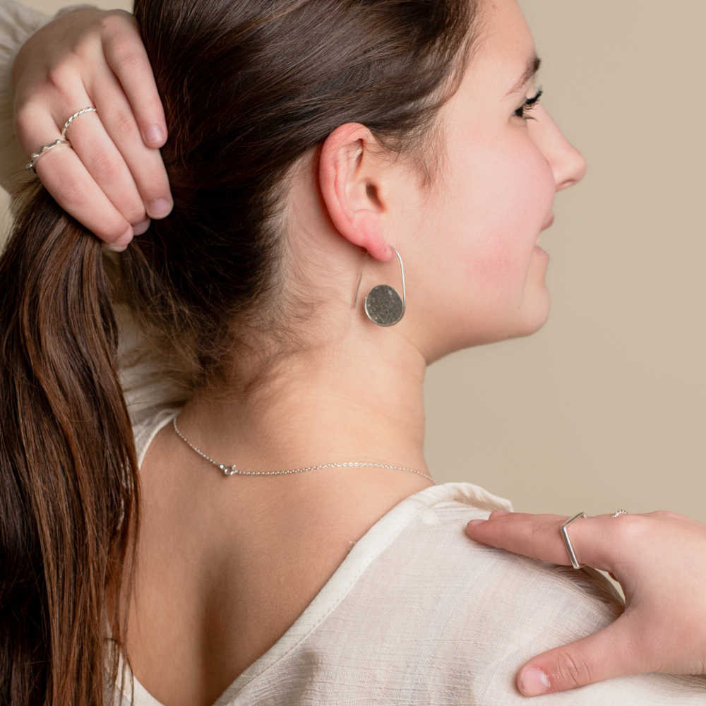 Modelo luciendo diversos anillos de plata y pendientes Luna Llena